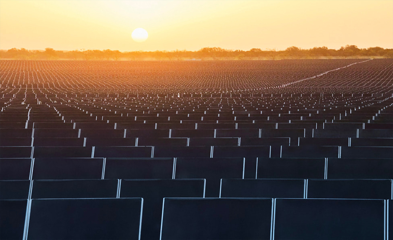 Centenas de painéis solares com o pôr-do-sol em segundo plano.