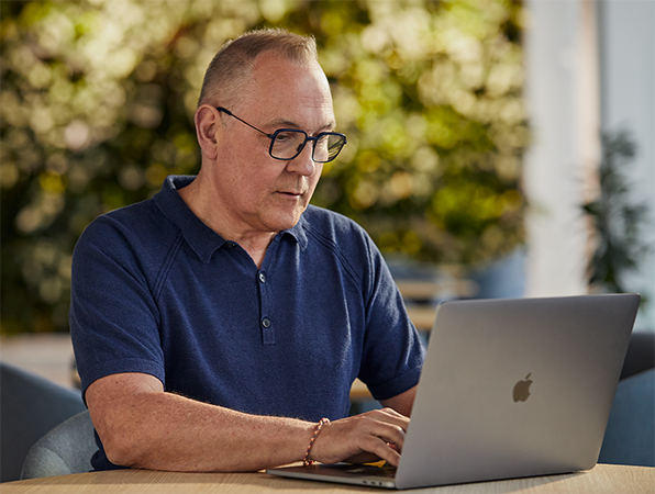 녹음이 우거진 야외에서 MacBook으로 작업하고 있는 Apple 소프트웨어 및 서비스 직원.