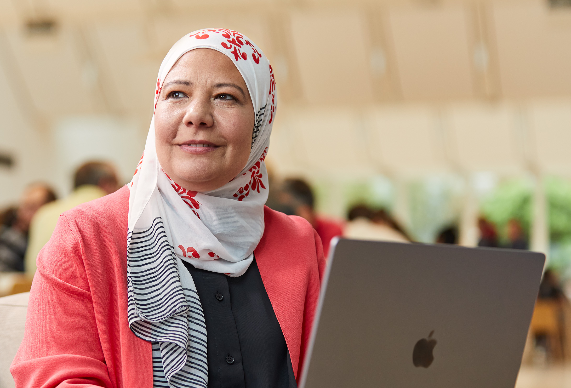 자리에 앉아서 MacBook으로 작업하며 왼쪽을 바라보고 있는 Apple 직원.