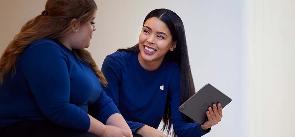 Carissa holding an iPad and talking with another Apple Retail employee.