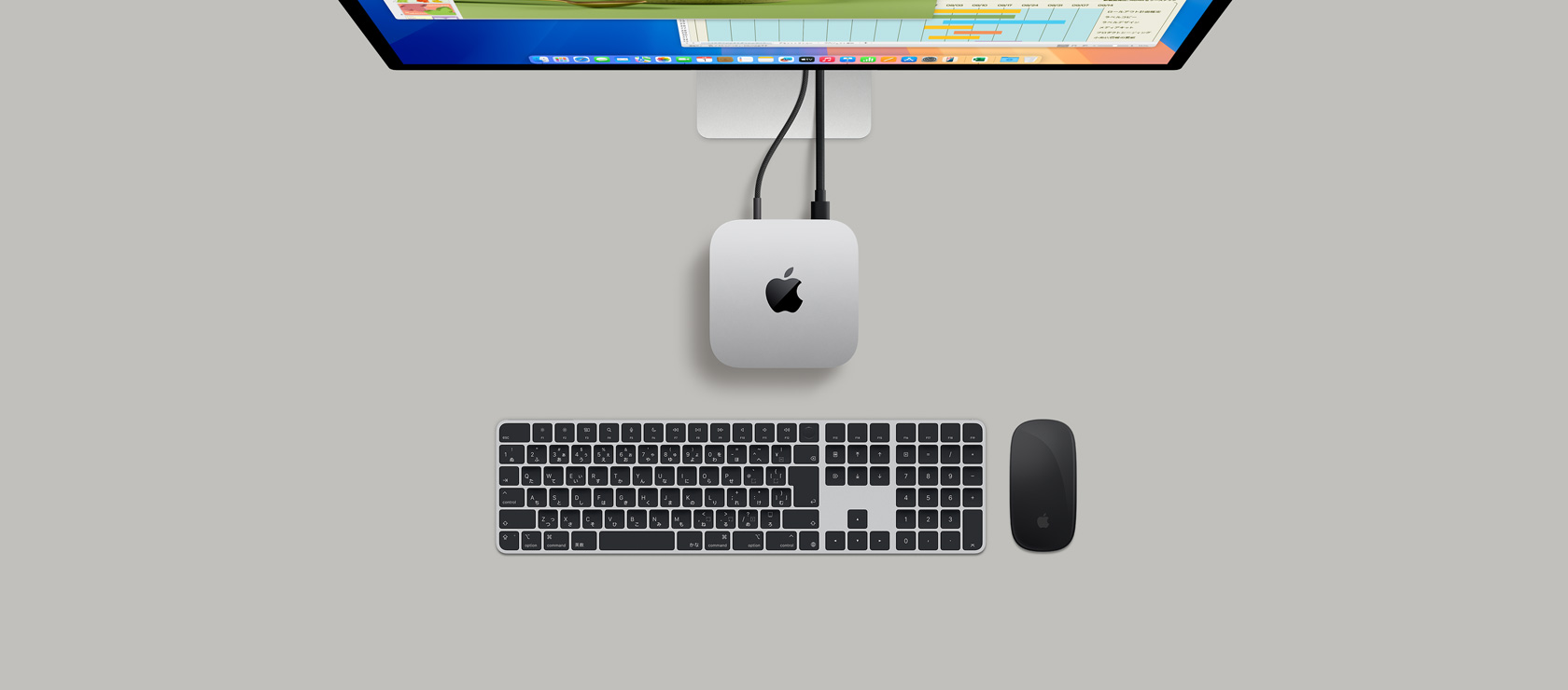 ディスプレイにつながれたシルバーのMac miniを上から見た図。ディスプレイにはKeynoteとMicrosoft Excelのウインドウが表示されている。