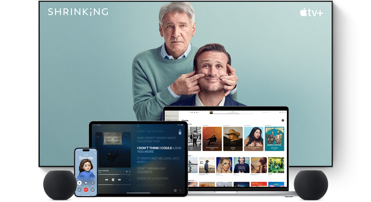 ทีวีจอแบนขนาดใหญ่แสดงตัวละครชายสองคนจากซีรีส์เรื่อง Shrinking ของ Apple TV+ โดยมี MacBook Pro, iPad, iPhone และ HomePod mini สีมิดไนท์วางอยู่ด้านหน้า