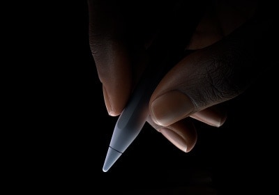 Користувач тримає нижню частину Apple Pencil Pro між великим і вказівним пальцями, ніби збирається писати.