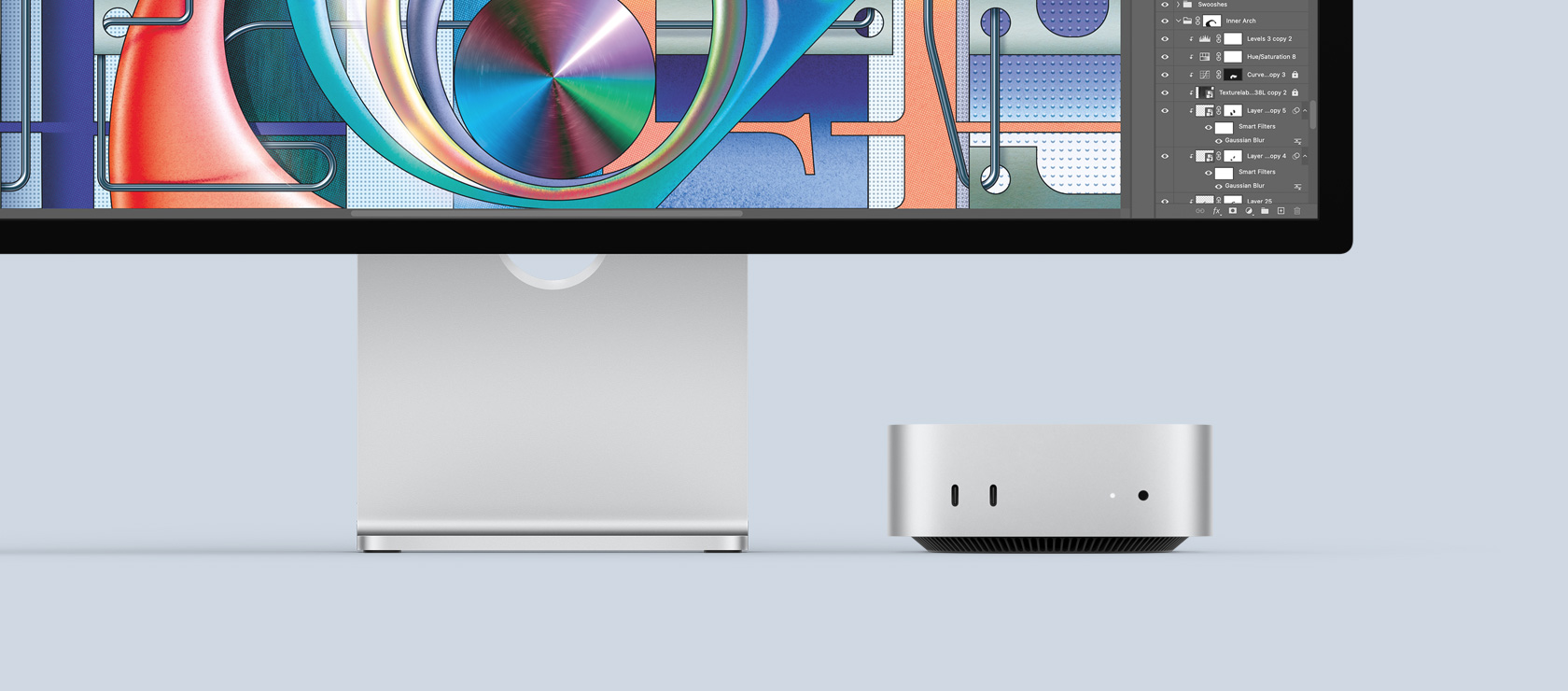 Front view of silver Mac mini showing front ports and indicator light fitting neatly underneath a Mac monitor showing a colourful screen